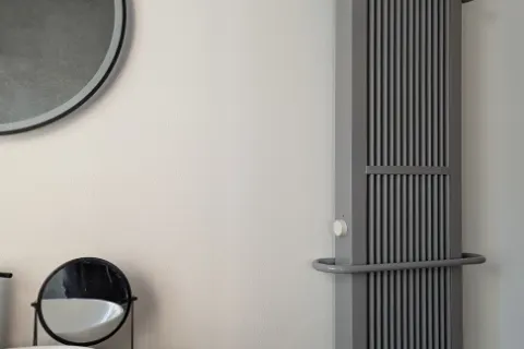 Graue Flächenspeicherheizung 35 × 120 cm mit zwei Bügeln an der Wand