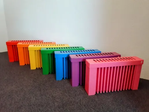 Sieben Flächenspeicherheizungen in Regenbogenfarben nebeneinander