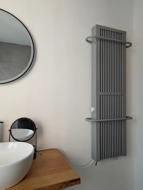 Graue Flächenspeicherheizung 35 × 120 cm mit zwei Bügeln an der Wand